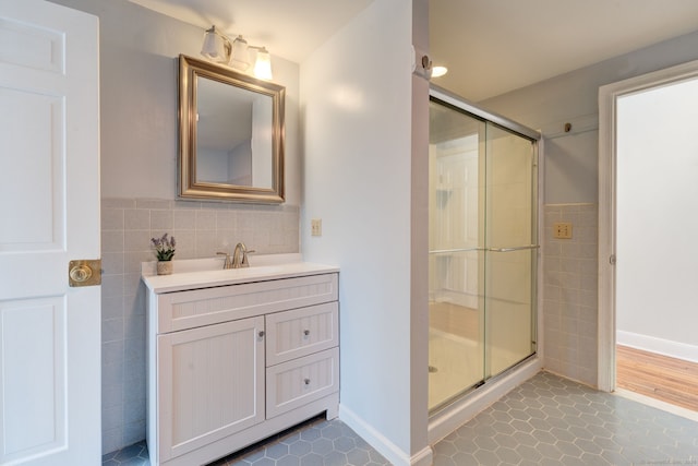 full bathroom featuring a stall shower, tile walls, vanity, and tile patterned floors