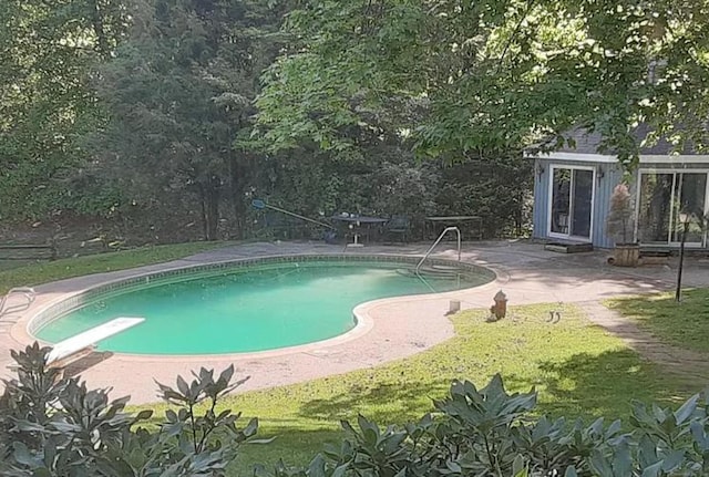 outdoor pool with a diving board and a patio