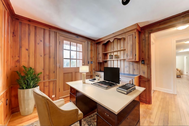 home office with light wood-style floors, wooden walls, baseboards, and crown molding