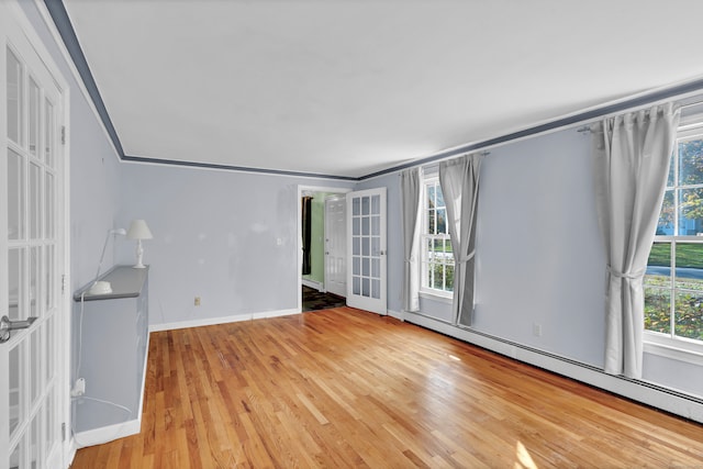 spare room with a baseboard radiator, french doors, ornamental molding, and light wood-type flooring