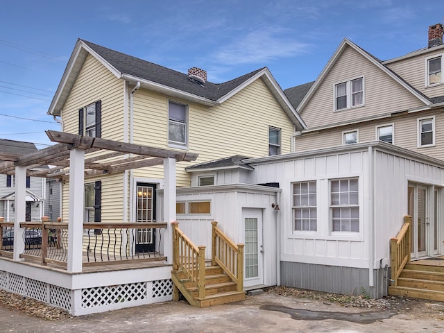 rear view of house with a wooden deck and a pergola