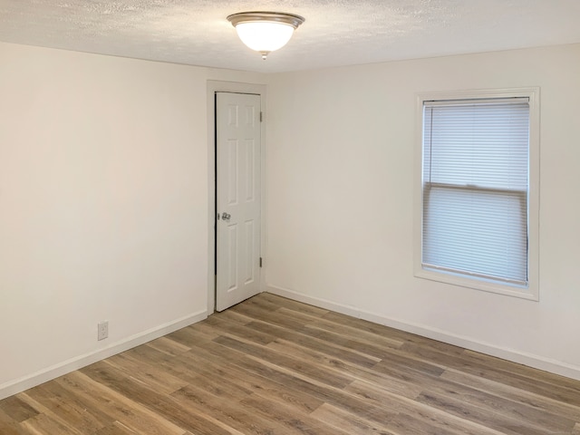 spare room featuring a textured ceiling and hardwood / wood-style flooring