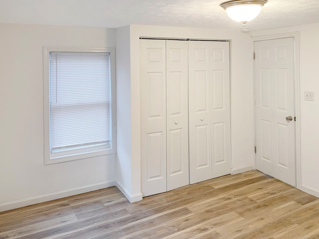 unfurnished bedroom with a closet, a textured ceiling, and light wood-type flooring