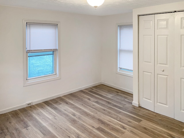 unfurnished bedroom with a closet, a textured ceiling, and hardwood / wood-style flooring