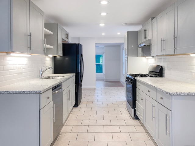 kitchen featuring sink, decorative backsplash, light stone countertops, and stainless steel appliances