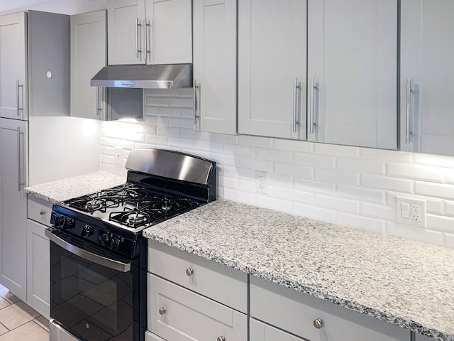 kitchen with light stone counters, light tile patterned floors, backsplash, and stainless steel gas range