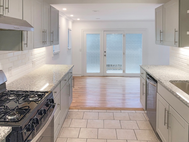 kitchen featuring a wealth of natural light, range hood, appliances with stainless steel finishes, and light hardwood / wood-style floors