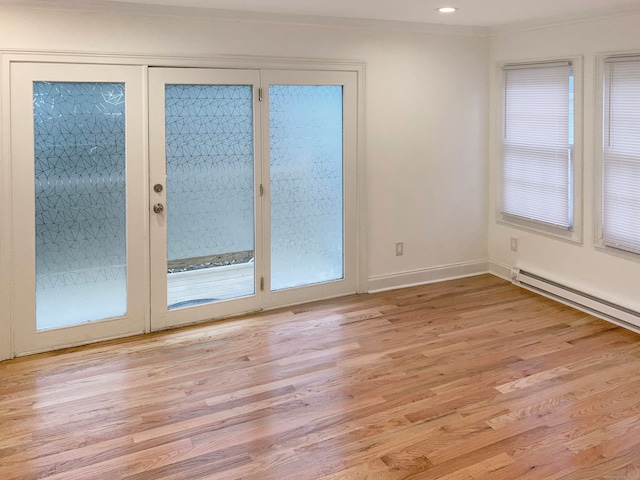 interior space with a baseboard heating unit and light hardwood / wood-style floors