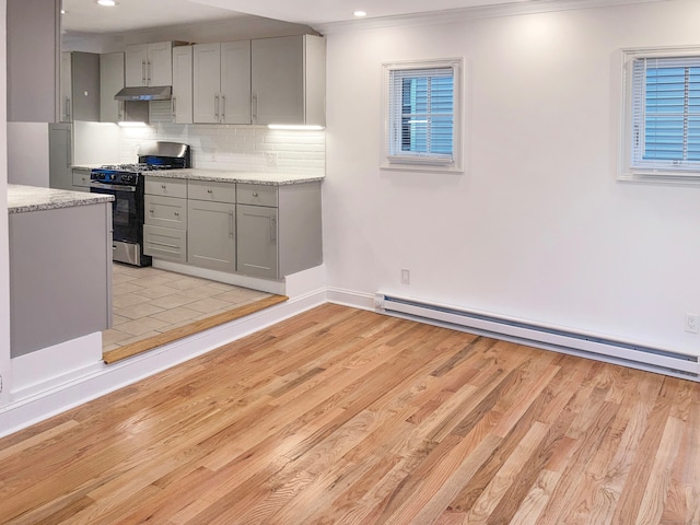 kitchen featuring a baseboard radiator, light wood-type flooring, backsplash, stainless steel range with gas cooktop, and gray cabinets