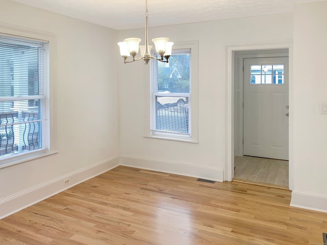 unfurnished dining area with a chandelier and light hardwood / wood-style floors