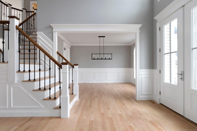 foyer entrance featuring a wealth of natural light, light wood-style flooring, and crown molding