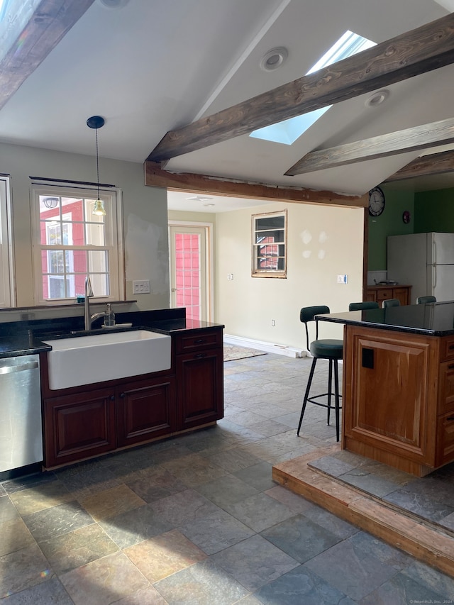 kitchen with a kitchen bar, stainless steel dishwasher, sink, pendant lighting, and white refrigerator