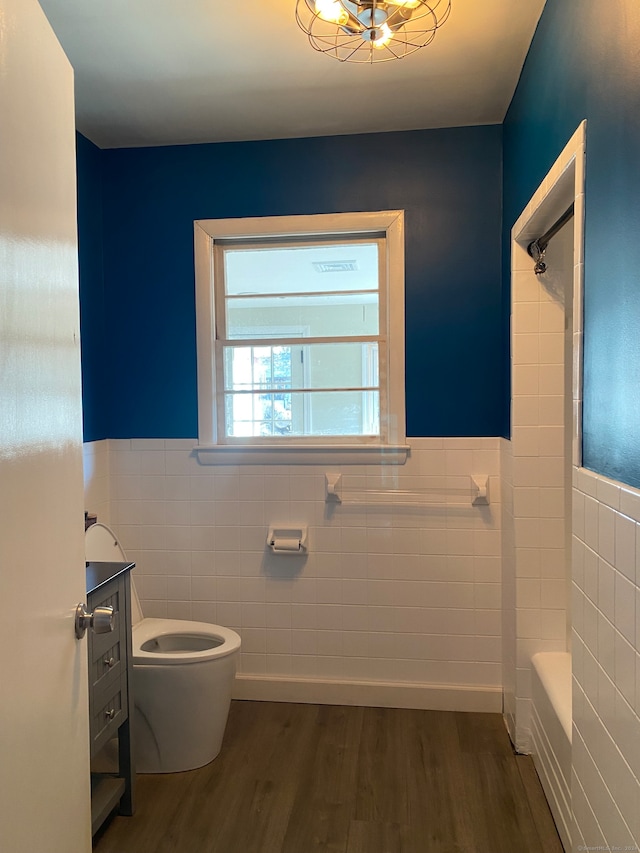 bathroom featuring hardwood / wood-style flooring, toilet, and tile walls