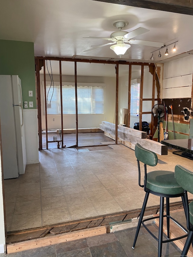 basement with white fridge and ceiling fan