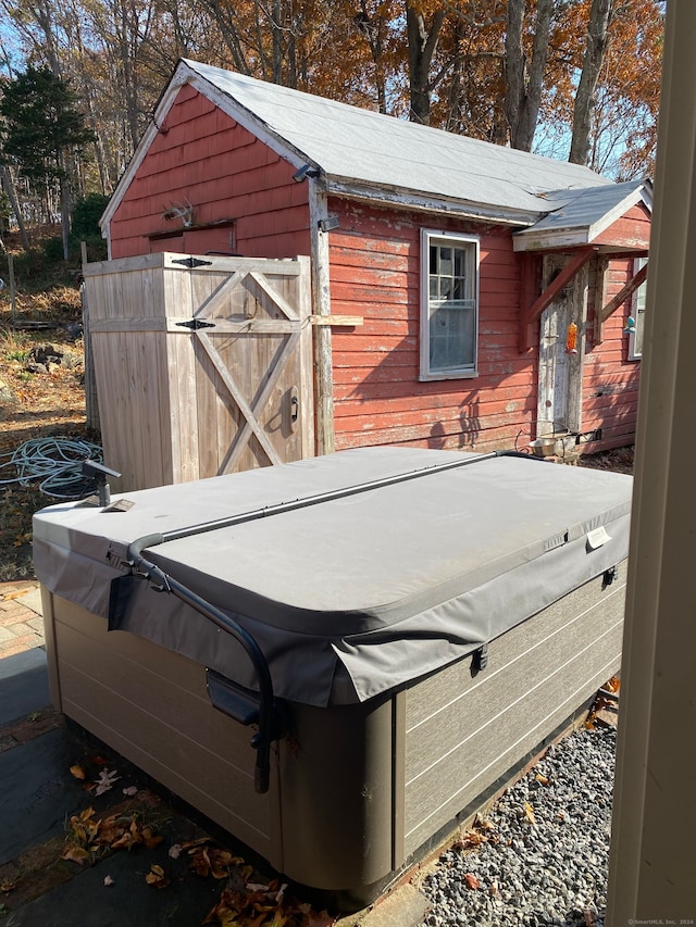 wooden terrace featuring a hot tub and a storage unit