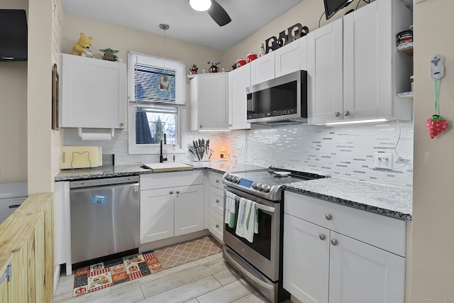 kitchen featuring tasteful backsplash, appliances with stainless steel finishes, sink, decorative light fixtures, and white cabinets