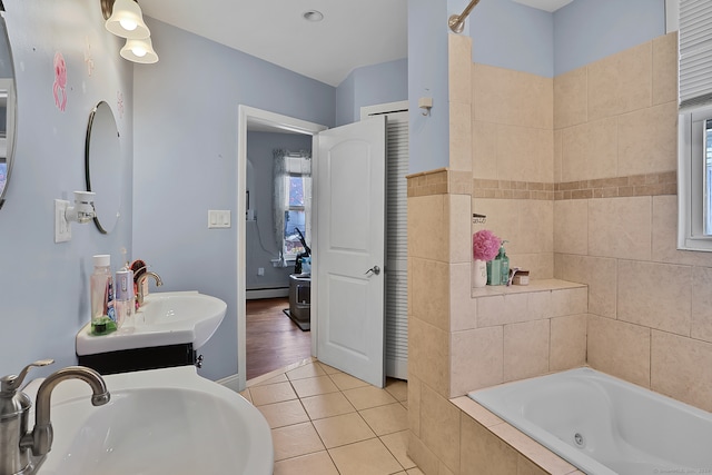 bathroom with vanity, a relaxing tiled tub, a baseboard radiator, and tile patterned flooring