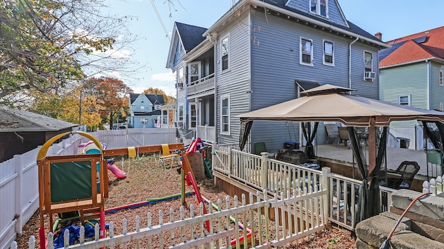 back of property featuring a gazebo and a playground