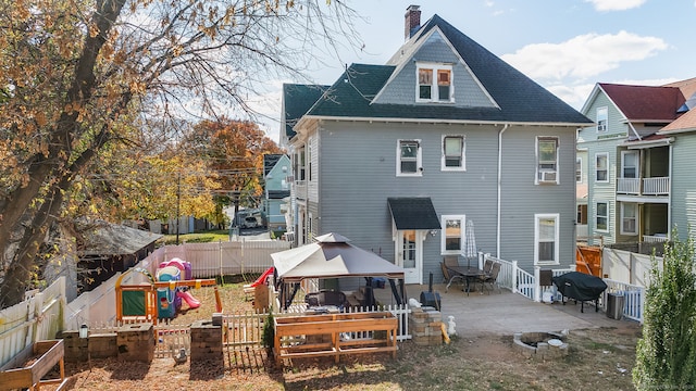 back of house with a gazebo and a playground