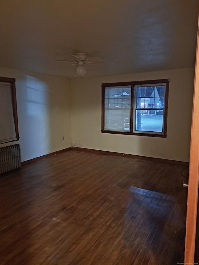 empty room featuring radiator heating unit, dark hardwood / wood-style floors, and ceiling fan