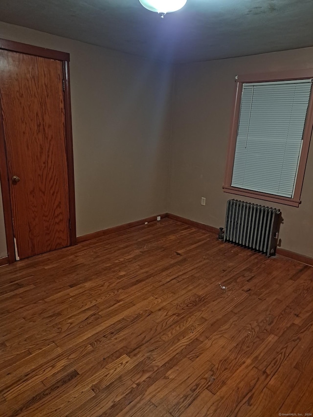 spare room with dark hardwood / wood-style floors and radiator heating unit