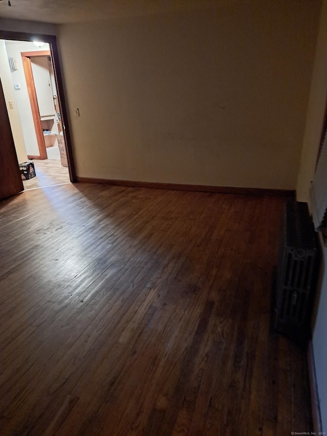 empty room featuring dark hardwood / wood-style flooring and radiator