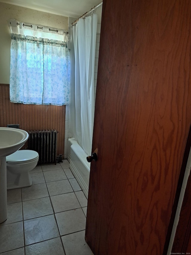 bathroom with radiator, tile patterned flooring, wood walls, shower / bath combination with curtain, and toilet