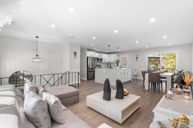 living room with a chandelier, sink, and light wood-type flooring