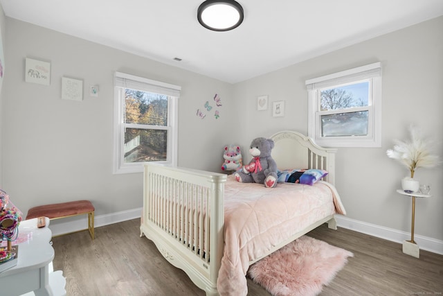 bedroom featuring multiple windows and dark hardwood / wood-style floors