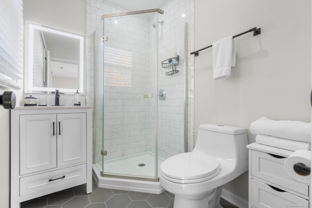 bathroom featuring vanity, a shower with shower door, toilet, and tile patterned floors