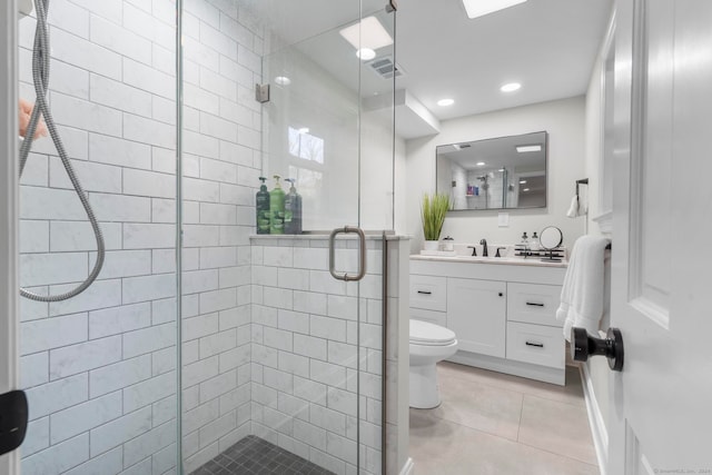 bathroom with toilet, a shower with shower door, vanity, and tile patterned floors