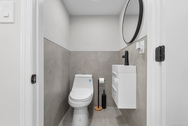 bathroom featuring toilet, vanity, tile patterned floors, and tile walls