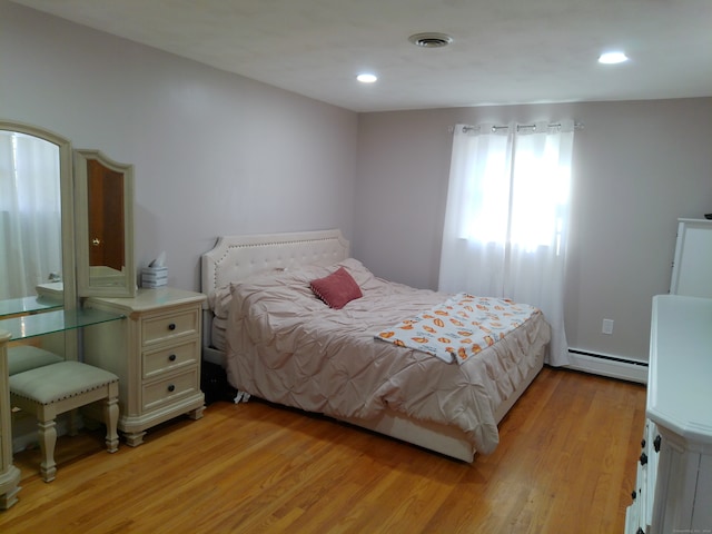 bedroom with baseboard heating and light hardwood / wood-style flooring