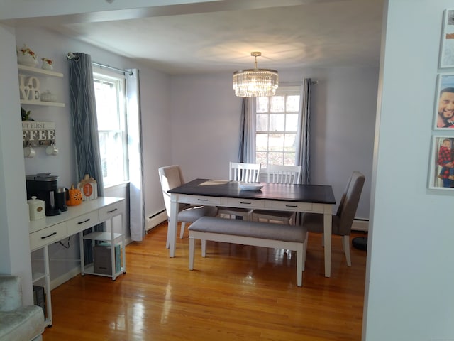 dining space with light hardwood / wood-style floors, a baseboard heating unit, and a chandelier