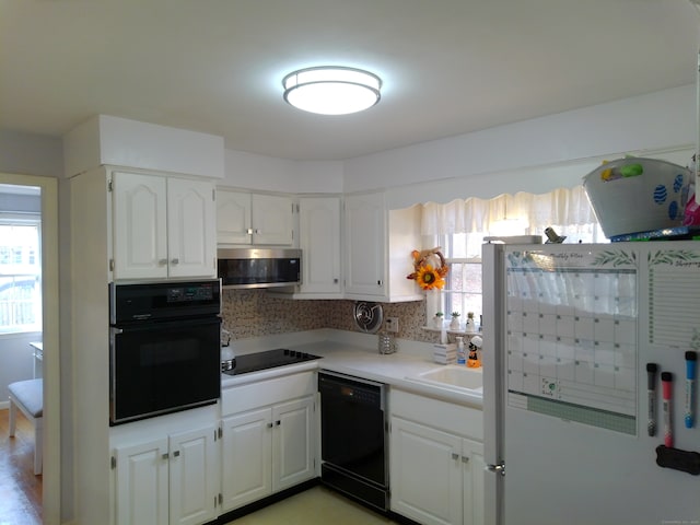 kitchen with black appliances, white cabinets, backsplash, and plenty of natural light