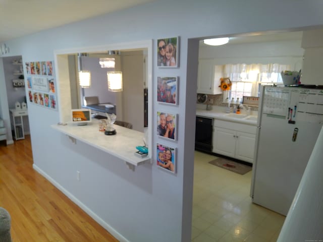 kitchen with sink, dishwasher, light hardwood / wood-style floors, white cabinets, and white refrigerator