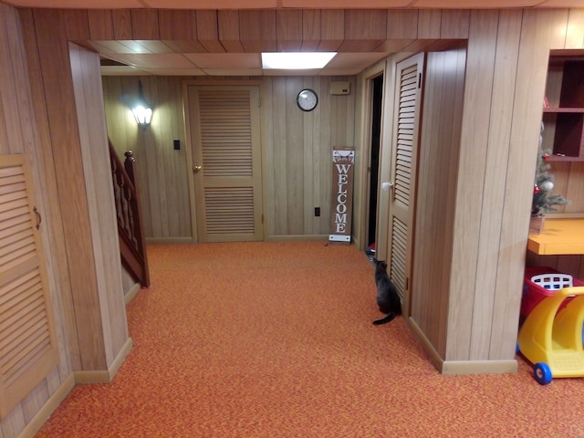 hall featuring light carpet and wood walls