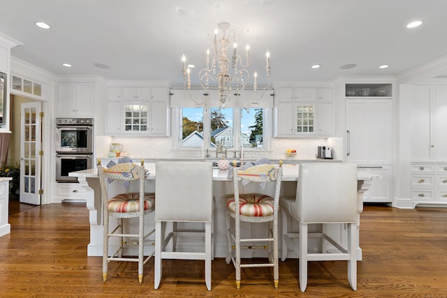 kitchen with white cabinetry, a kitchen breakfast bar, double oven, and a kitchen island