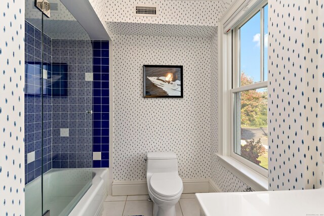 full bathroom featuring tile patterned floors, toilet, tiled shower / bath combo, and plenty of natural light