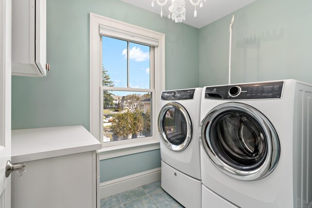 washroom featuring cabinets, light tile patterned flooring, an inviting chandelier, and washer and clothes dryer