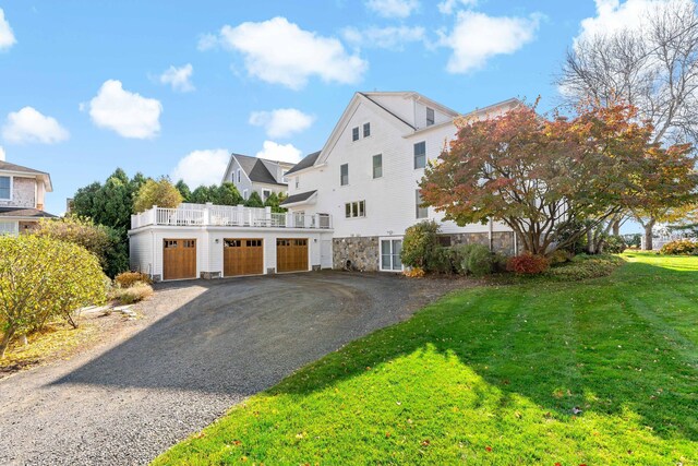 view of front of property featuring a balcony, a front yard, and a garage