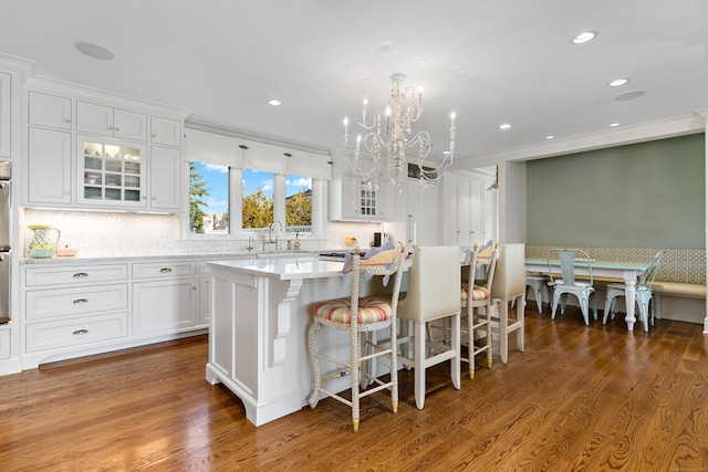 kitchen featuring a kitchen island, dark wood-type flooring, a breakfast bar area, and white cabinets