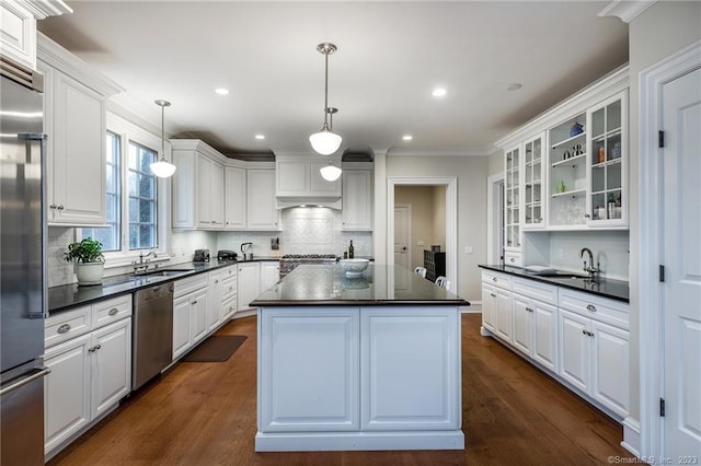 kitchen with white cabinets, dark hardwood / wood-style flooring, a kitchen island, pendant lighting, and stainless steel appliances