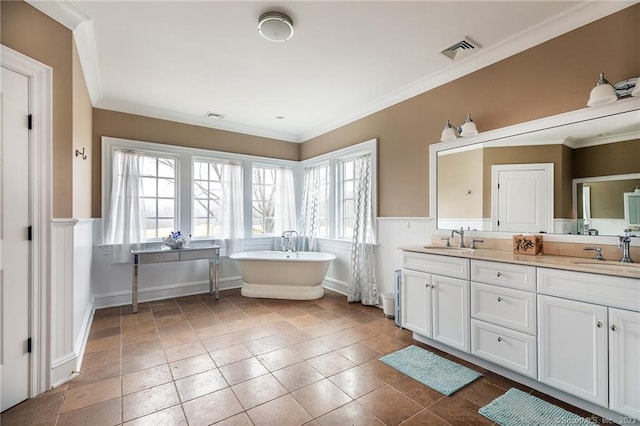 bathroom featuring vanity, ornamental molding, a wealth of natural light, and a bathing tub