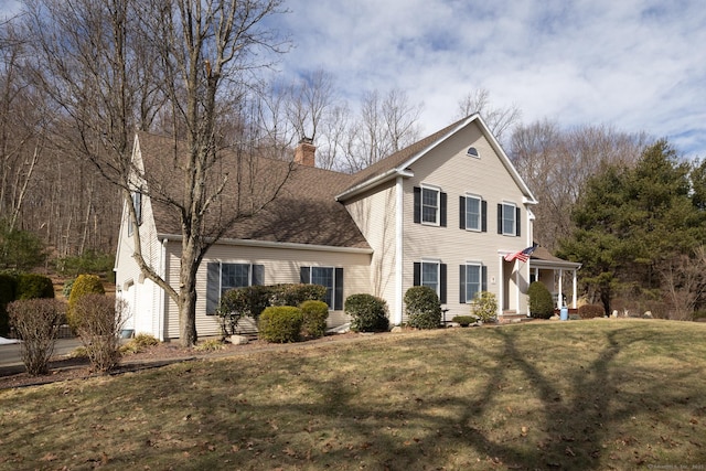 view of front of property featuring a front yard, roof with shingles, and a chimney