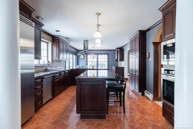 kitchen featuring a kitchen bar, island range hood, dark brown cabinets, and appliances with stainless steel finishes