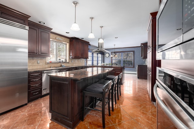 kitchen with a kitchen island, stainless steel appliances, dark brown cabinetry, a breakfast bar area, and crown molding