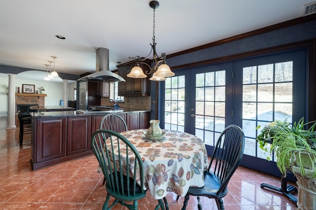 dining space with decorative columns, visible vents, plenty of natural light, and ornamental molding