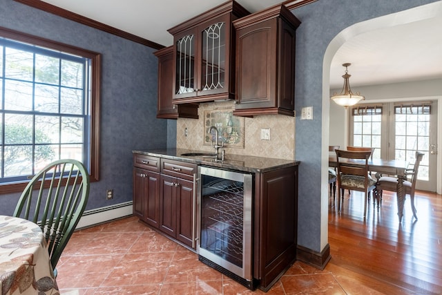 kitchen with a healthy amount of sunlight, a sink, wine cooler, and dark stone countertops