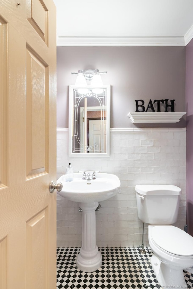 half bathroom with wainscoting, toilet, tile walls, and ornamental molding